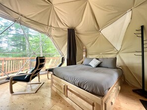 A tented room with a bed, a lounge chair, and a view of the outdoors. - Dome #3 Located in the heart of nature. (Saint-Gabriel-de-Valcartier)