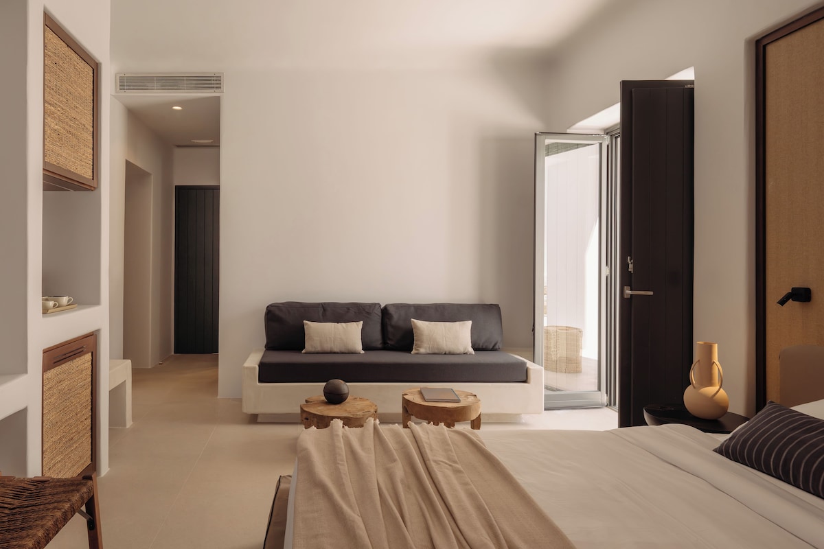 A modern hotel room with a sofa, a bed, a small table, and a chair.