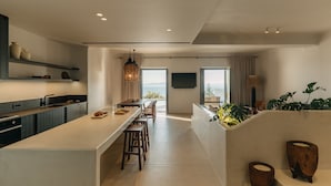 A modern kitchen with a long island, bar stools, and a view of the ocean. - Bard De Sol (Mykonos)