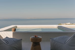 A rooftop terrace with a pool, two grey cushioned chairs, and a small table with a plate and a vase. - Bard De Sol (Mykonos)