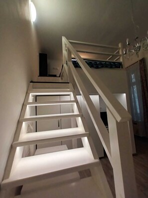 A staircase with white railings and a handrail, leading to an upper floor. - Opera Sweet Home  (Budapest)