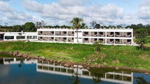 A multi-story hotel with balconies, a pool, and a reflection in the water. - HOTEL VISTA LAGO (La Pena)