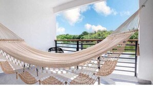 A hammock suspended between two white walls in a room with a balcony. - HOTEL VISTA LAGO (La Pena)