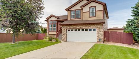 A two-story house with a stone facade, a garage, and a well-maintained lawn.