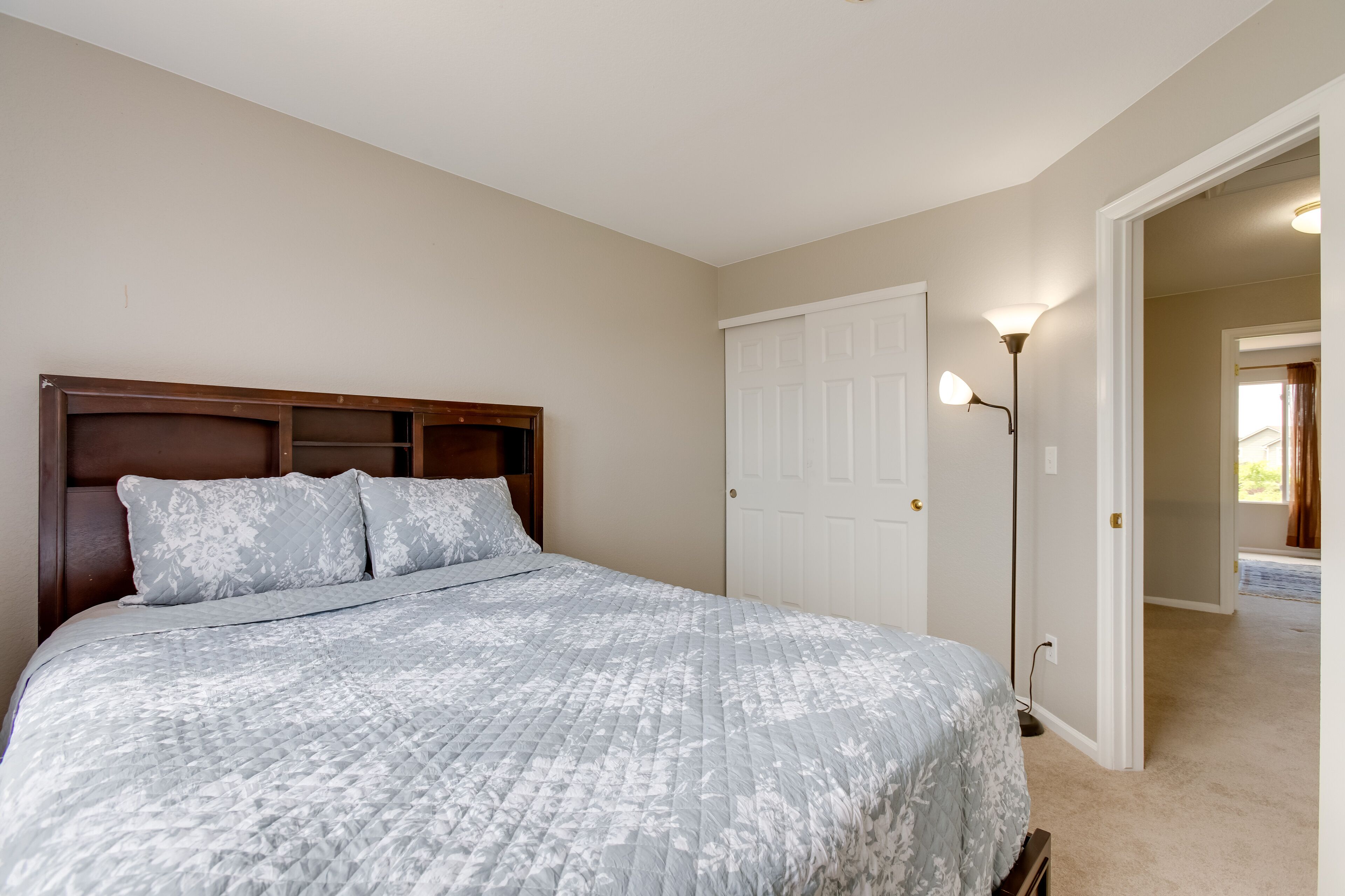 Une chambre à coucher comprenant un lit, une table de chevet, une lampe et une porte donnant sur une autre pièce.