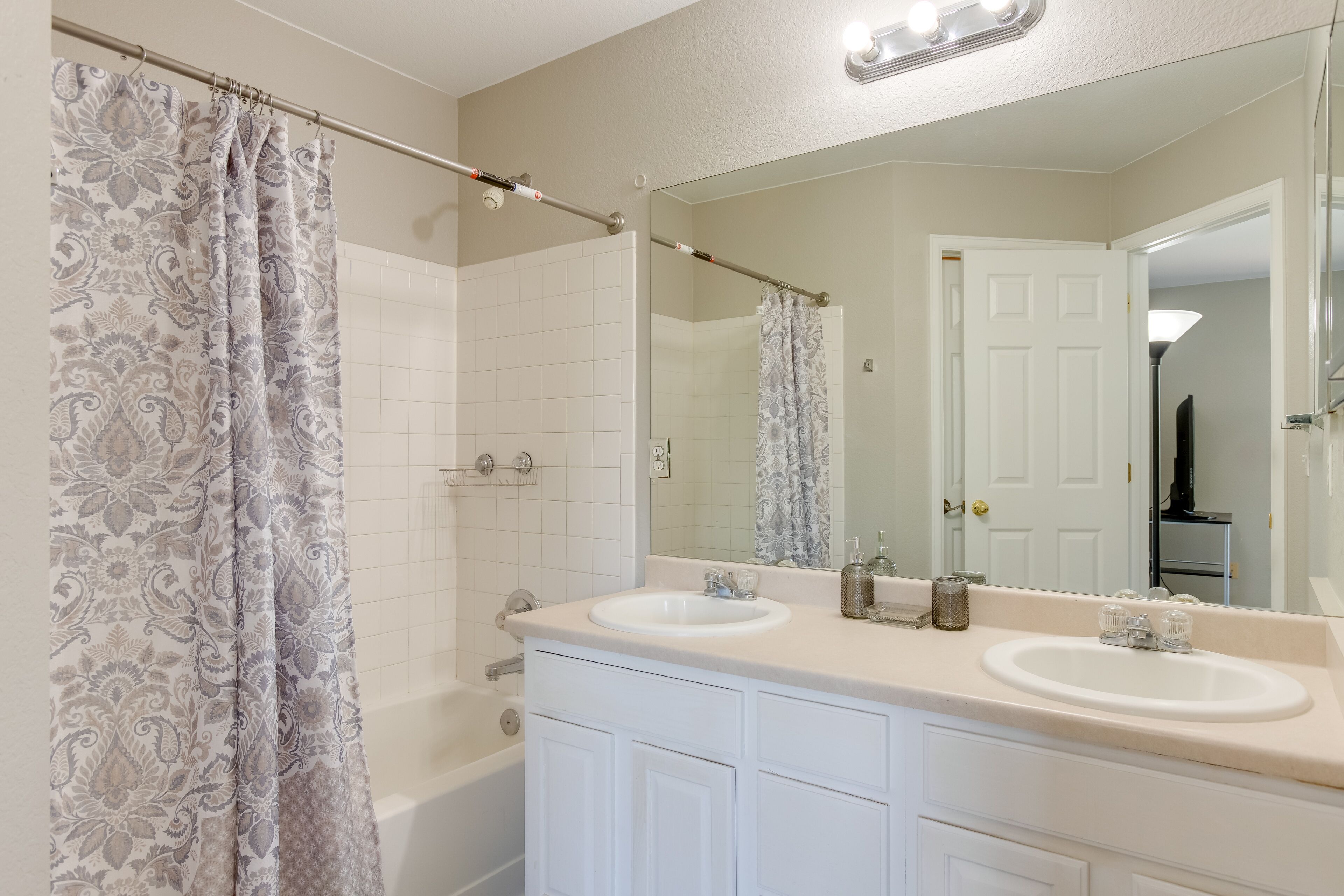 A bathroom with two sinks, a large mirror, and a shower curtain.