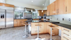 A modern kitchen with stainless steel appliances, wooden cabinets, and a large island with bar stools. - Spacious King of Prussia Home w/ 2 Game Rooms (King of Prussia)