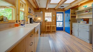 Una cocina amplia con vigas de madera, un ventanal grande y una puerta azul.