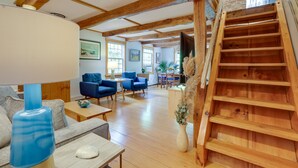 Un salón espacioso con escalera de madera, un sofá, una mesa de centro y una lámpara.