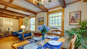 Un comedor con una mesa de madera dispuesta para cuatro, individuales azules y un jarrón con flores azules.