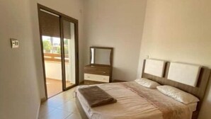 Une chambre à coucher comprenant un lit, une table de chevet et une porte-fenêtre coulissante donnant sur un espace extérieur.