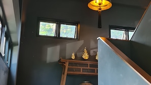 En trappa med modern design som leder upp till en mörk vägg med två fönster och en dekorativ hylla.