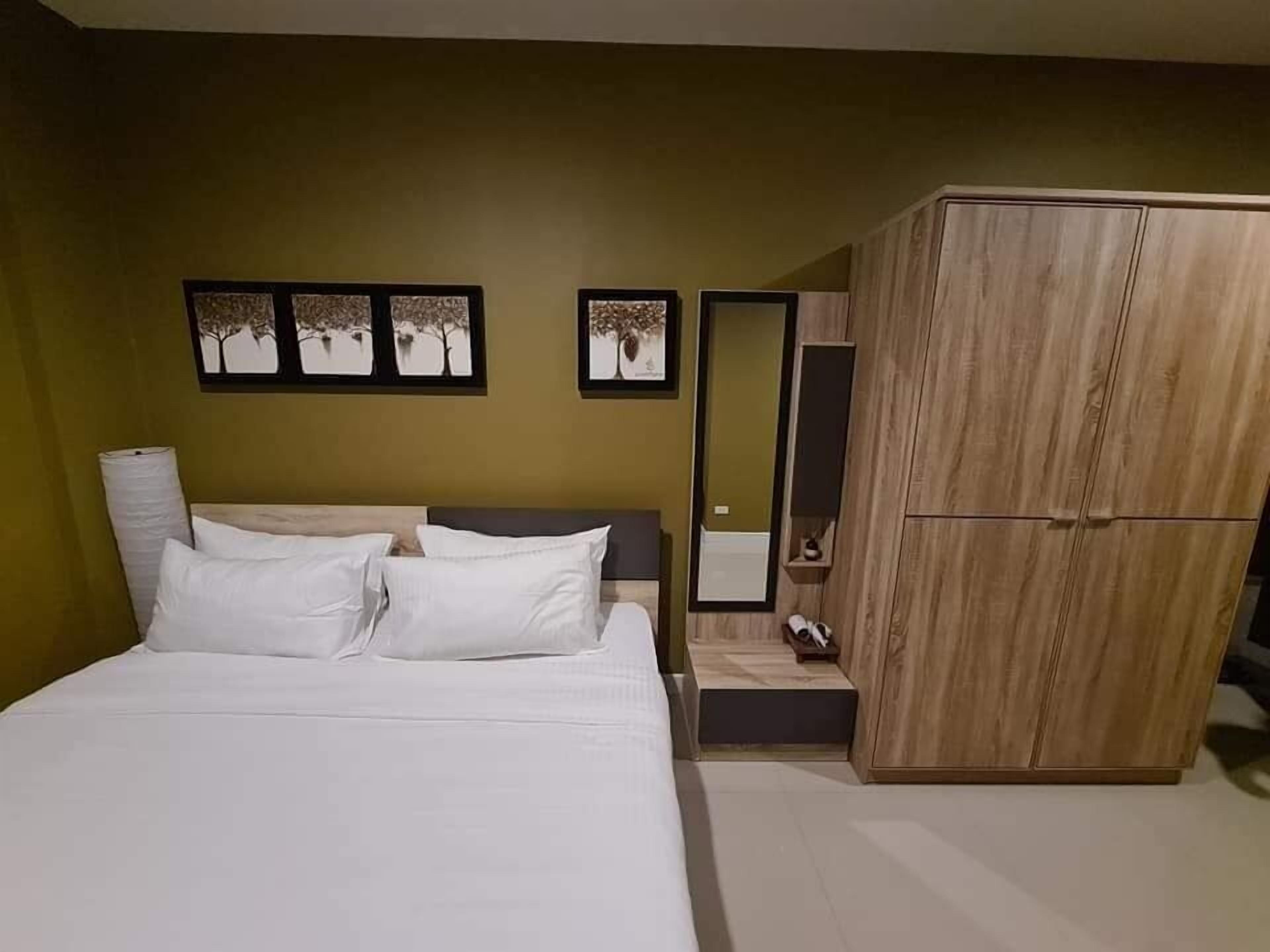 Een slaapkamer met een bed, een kledingkast en drie ingelijste foto’s aan de muur.