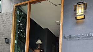 En modern entré till en byggnad med en stor glasdörr, en träram och en skylt med texten ”Eastern Suite”.