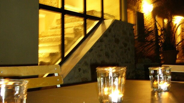 Une table avec des bougies et une chaise, un escalier et la façade d’un immeuble avec des fenêtres.