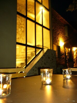 A table with candles and a chair, a staircase, and a building facade with windows. - Mas Boudeissoun - Grain de Muscat - Baignade à 600 m (Mormoiron)
