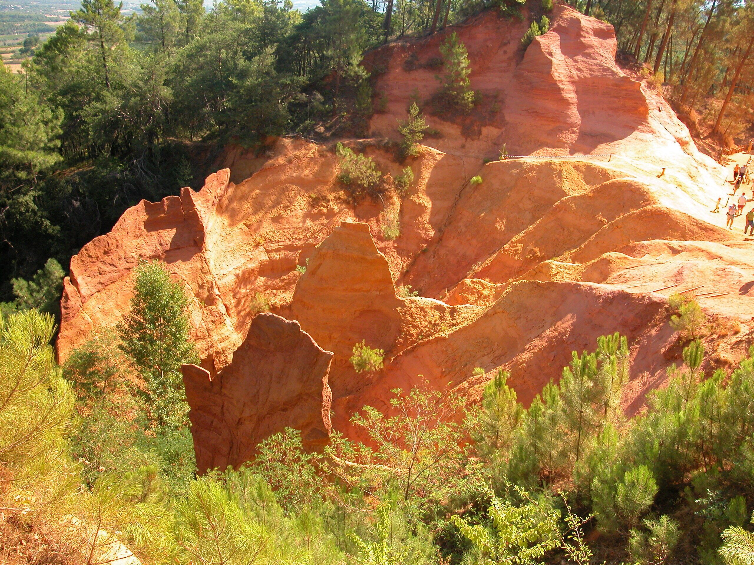 Eine zerklüftete Landschaft mit roten Felsformationen und üppigen grünen Bäumen.