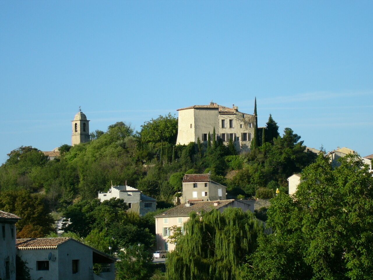 Un bâtiment perché sur une colline, doté d’un clocher, entouré d’arbres et d’immeubles d’habitation.