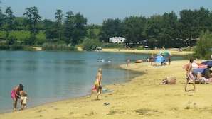 Une plage de sable où l’on voit des gens, des tentes et un lac.