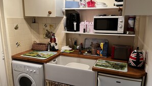 Cocina compacta con lavadora, microondas, tostadora y un refrigerador pequeño.