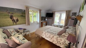 Un dormitorio acogedor con cama, sofá, una mesita y una estantería.