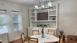 A dining area with a round table, four chairs, a vase with branches, and a modern chandelier. - Spacious charming farmhouse-style home - dedicated office (Burlington)