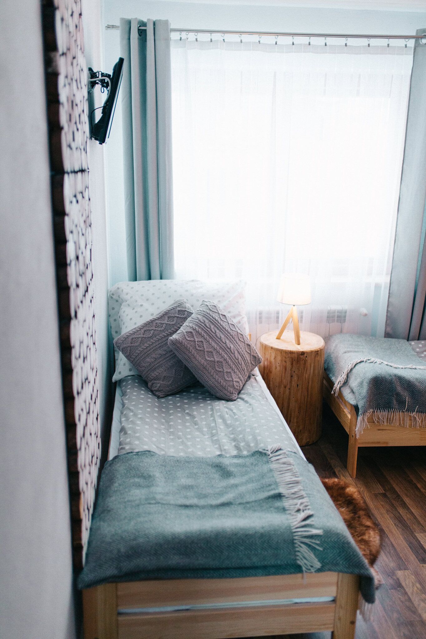 Un dormitorio pequeño y acogedor con una cama, una mesita de noche y una ventana con cortinas.
