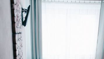 Un dormitorio pequeño y acogedor con una cama, una mesita de noche y una ventana con cortinas.