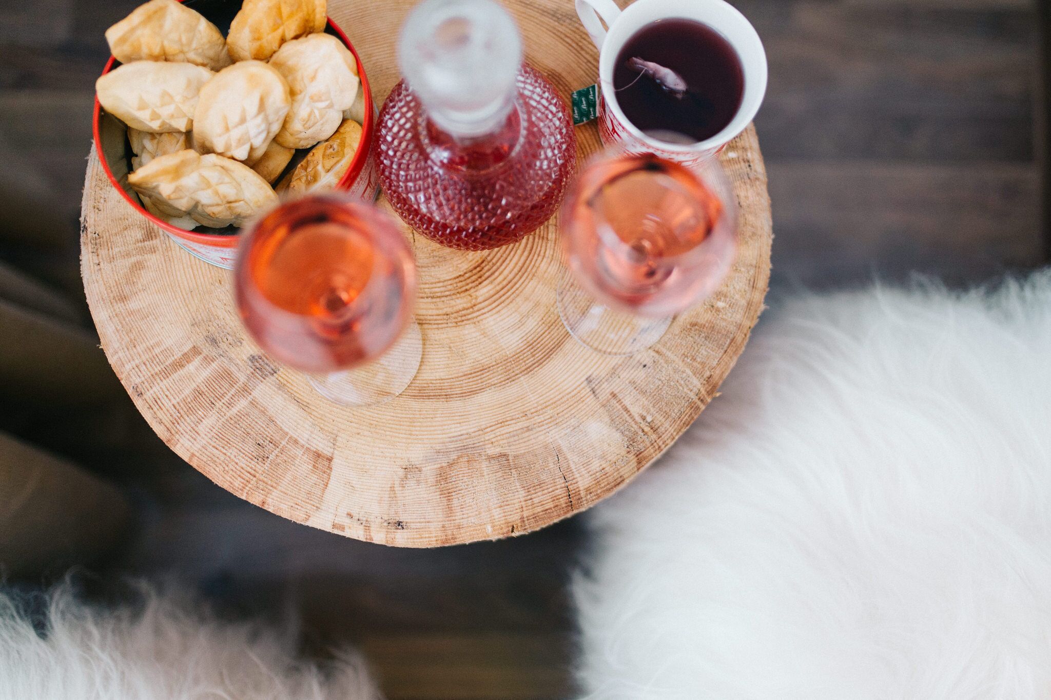 A wooden tray with pastries, a bottle, and two glasses of red wine.