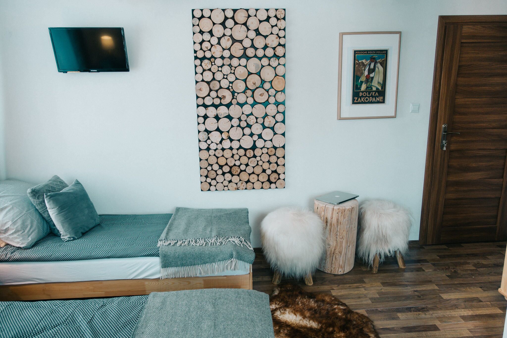 Ein Schlafzimmer mit Bett, Fernseher, Wandbild, einem Poster und einer Holztür.