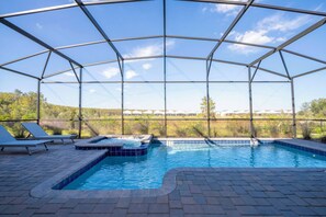 Una piscina esterna coperta con lettini e una vasca idromassaggio.