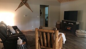 A cozy living room with a leather sofa, a wooden rocking chair, a fireplace, and a television. - Whitetail Hollow  (McBain)
