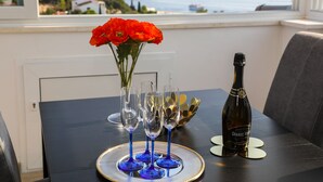 Et bord med en flaske Grande Varenne vin, en vase med røde blomster og fire blå vinglas på et fad.