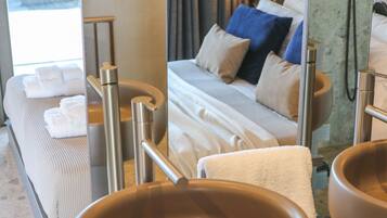 A hotel room with a bed, bedside tables, a large mirror, and a view of the sea.