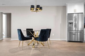Enjoy meals at the dining table with a glass top, surrounded by comfortable seating for four.