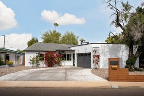 Stunning two-story home with a flat roof, garage, and beautifully landscaped yard.