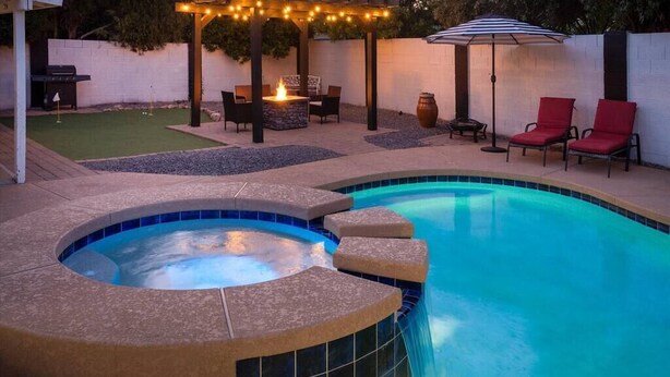 Ein Garten mit Schwimmbad, Whirlpool, Sitzgelegenheit und Grillplatz.