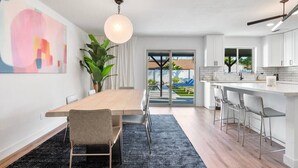 Uma cozinha moderna com uma ilha grande, armários brancos e vista para o exterior.