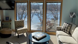 A living room with a large window overlooking a lake, a sofa, a chair, and a coffee table. - Lakeside Dreaming! 2b-2b, Sleeps 6, Lake of the Ozarks. (Gravois Mills)