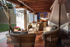 An outdoor patio with wicker furniture, a dining area, and a view of the garden. - Casa Laurel
 (Oaxaca de Juárez)