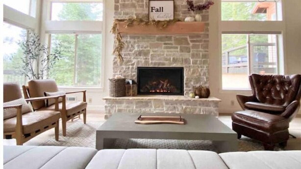 Una sala de estar acogedora con chimenea de piedra, un sillón de cuero y un sofá.