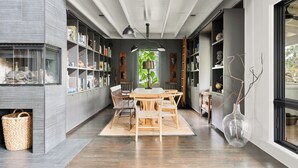 A modern dining area with a wooden table and chairs, surrounded by bookshelves and decorative items. - Hemingway | Jungle Hideaway (Folly Beach)