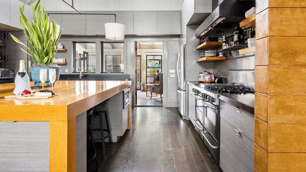 A modern kitchen with a wooden island, stainless steel appliances, and a large potted plant. - Hemingway | Jungle Hideaway (Folly Beach)