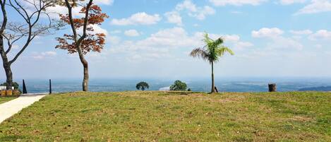 A grassy hill with a path leading to a viewpoint overlooking a valley.