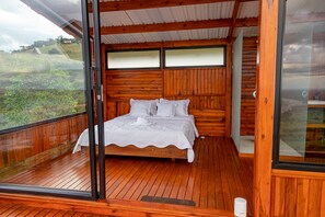 Een houten chalet met een groot bed, een balkon en uitzicht op het omliggende landschap.
