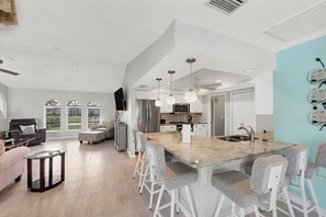 Een moderne keuken met een centraal eiland, barstoelen en hanglampen.