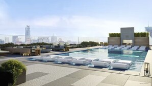 Uma área de piscina no terraço com espreguiçadeiras e um edifício moderno ao fundo.