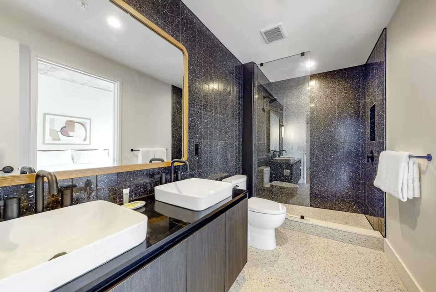 Ein modernes Badezimmer mit zwei Waschbecken, einer Toilette und einer Duschkabine.