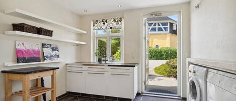 A modern kitchen with white cabinets, a wooden countertop, and a built-in washing machine.