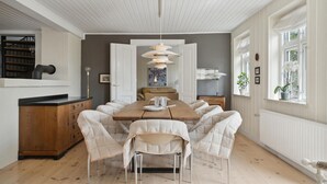 A dining area with a wooden table and six upholstered chairs, a pendant light, and a view of the outdoors through a window. - 4 bedroom nice home in Nyborg (Nyborg)